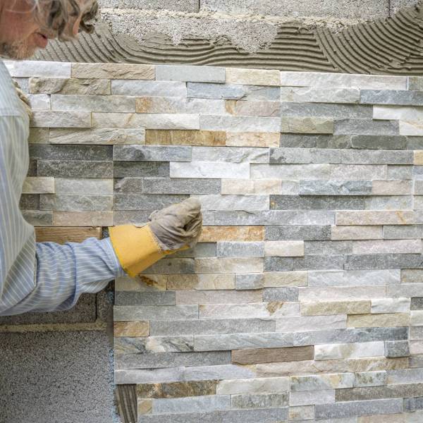 older-man-decorating-wall-with-ornamental-tiles-pressing-fixating-tile-firmly-into-glue-with-his-fist_1900x1268_600x600